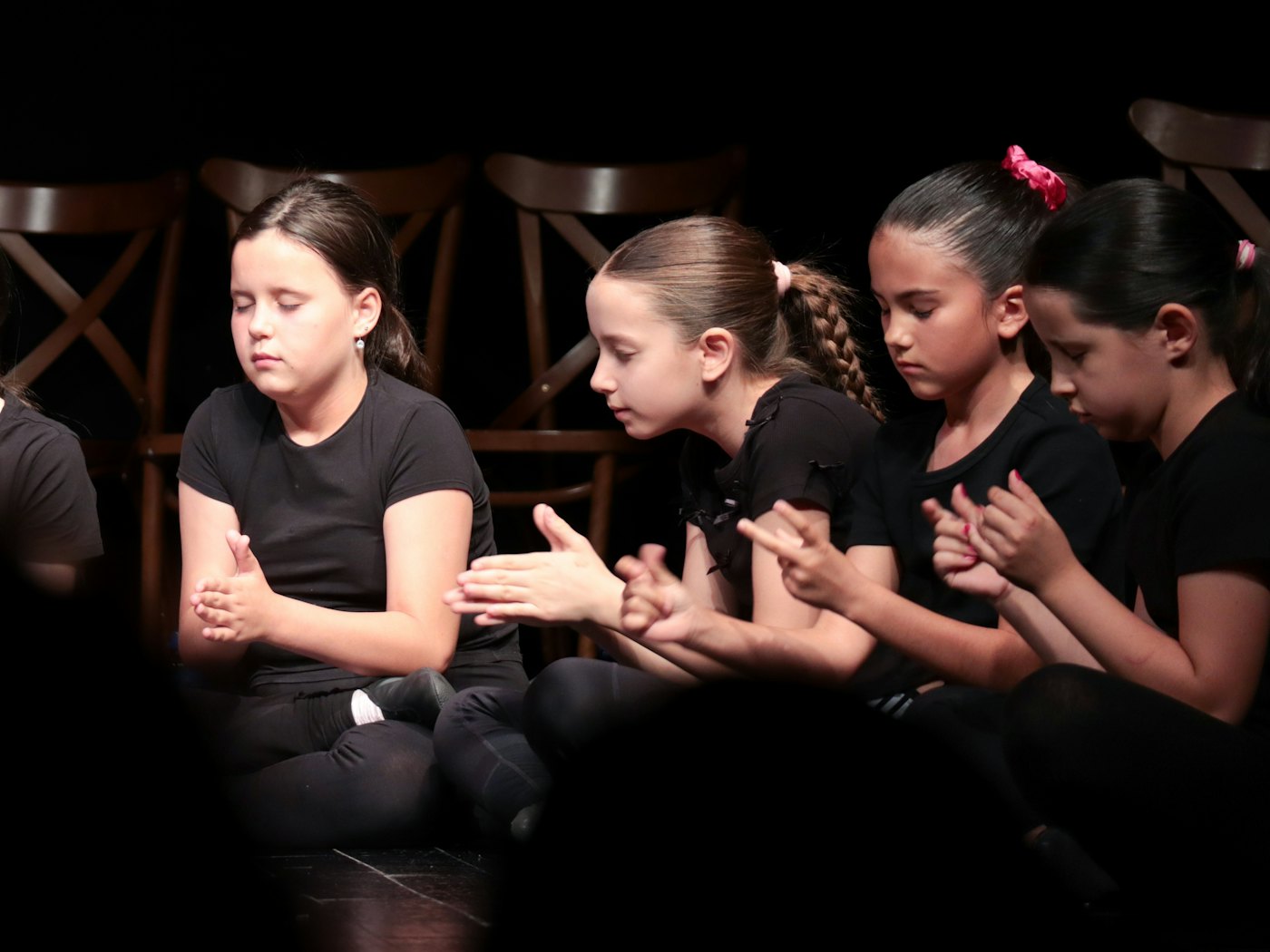Enfants assis en ligne sur une scène pendant un atelier de théâtre